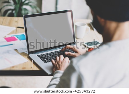 Photo bearded graphic designer working with new project modern loft.Using contemprary laptop on wood table.Creative process.Mock up notebook reflection screen.Blurred background,film effect,horizontal