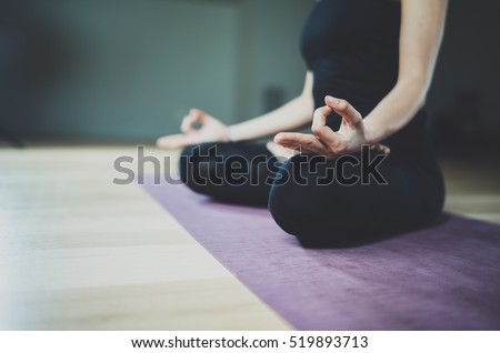 Close up view of young woman meditates while practicing yoga in a training hall. Freedom concept. Calmness and relax, female happiness.Horizontal, blurred garden on the background