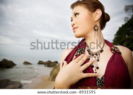 young woman wearing accessories of ear-rings and necklace by the sea side look out to the sea
