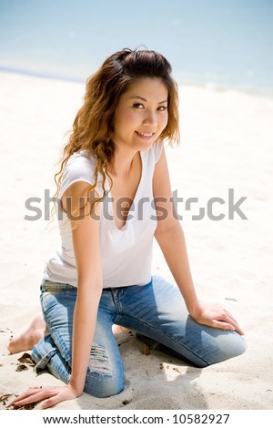 happy woman kneeling on the beach in casual wear