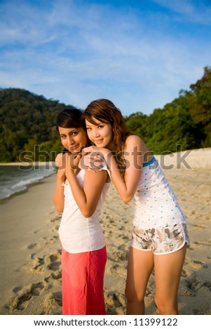 woman best friends hugging, standing by the sunset beach