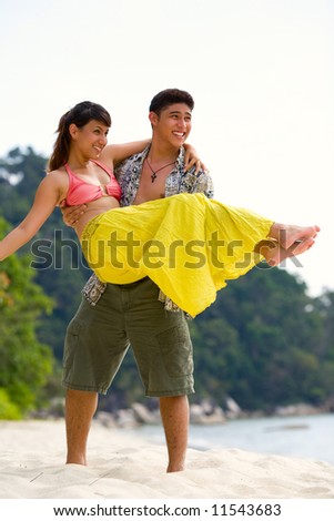 asian couple having fun as the guy carrying the girl on the beach
