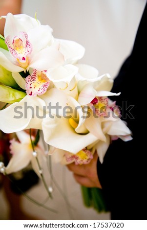 groom holding a bouquet of orchids and lilies