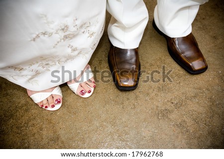 feet of bride and groom standing together in white wedding dress