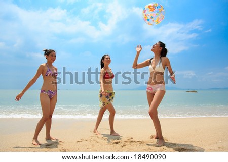 three beautiful young woman playing with a inflatable ball near the ocean