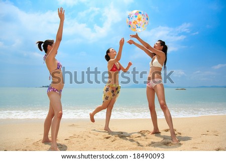 three Beautiful young woman playing with a inflatable ball near the ocean