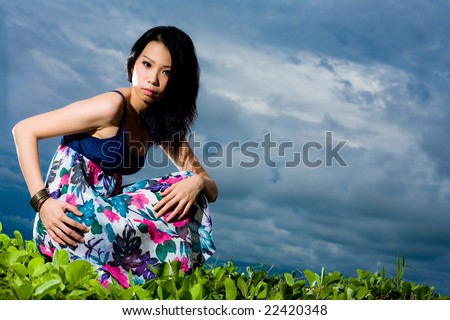asian woman squatting outdoor against blue sky