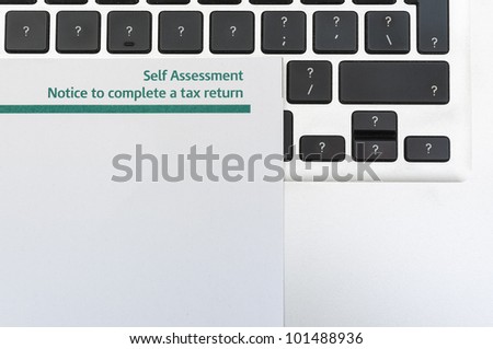Detail of blank tax return form on top of computer keyboard with question marks in all keys and lots of copy space.