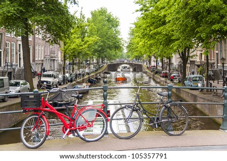 Detail of bicycles locked on top of bridge in Amsterdam, Holland, with traditional canal in the background.