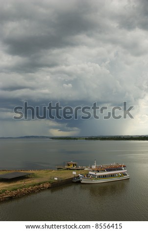Vertical seascape with boat in the shore and storm looming in the far horizon. 2/3 copy space