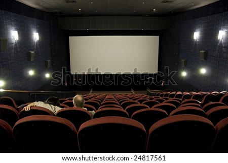 Mature couple in empty cinema, with blank silverscreen.