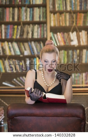 Beautiful caucasian woman reading book and looking surprised in old library