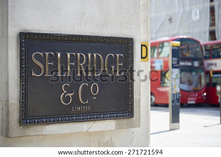 LONDON, UK - APRIL 22: Shop sign at the corner of famous department store Selfridge & Co., in Oxford Street, with red double-decker bus in the background. April 22, 2015 in London.