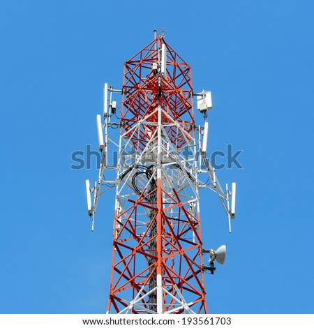 Telecommunication mast with microwave link and TV transmitter antennas on blue sky.