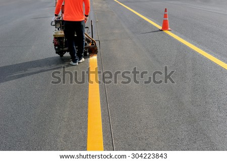 Workers are painted traffic lines with spraying machines.