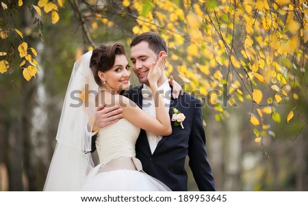 Newly married couple posing in autumn park