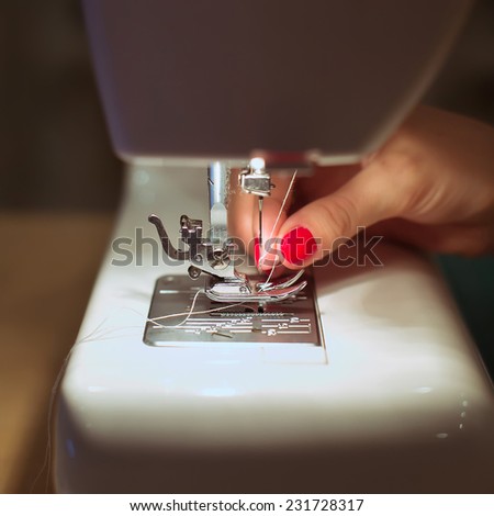 Close-up female hands sewing fabric on sewing machine