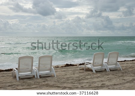 Four lonely chairs in rough weather at the shoreline in Florida