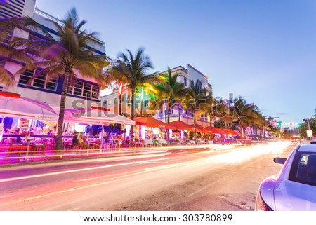 MIAMI, FLORIDA - JUNE 21, 2015: Cars speed down Ocean Drive. The road is the main thoroughfare through South Beach, Miami. Ocean Drive scene at night lights, cars and people having fun, Miami beach.