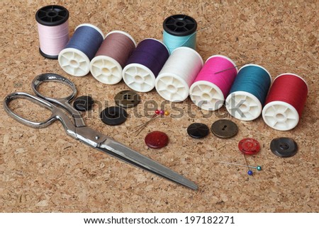 Sewing items: buttons, material, measuring tape, bobbins, buttons, cloth, safety pins, needles, spools of thread,  scissors