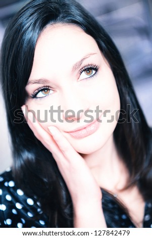 Closeup portrait of cheerful young woman with hand on face