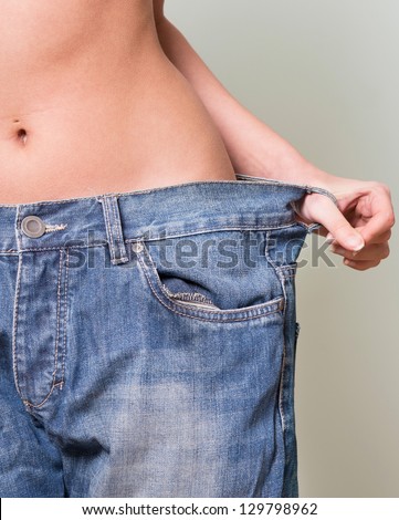 Successful weight loss, woman with too large jeans after a diet