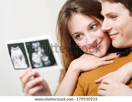 Beautiful couple watching with emotion sonography pictures of their baby Beautiful couple watching with emotion sonography pictures of their baby