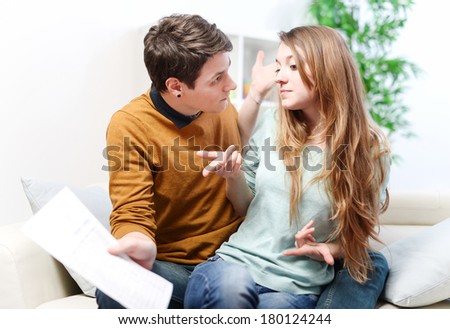 Young anxious couple quarrels by consulting their bank account