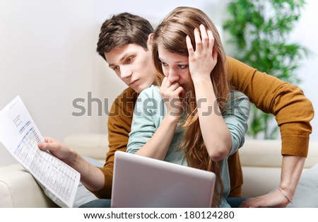 Young anxious couple consults their bank account