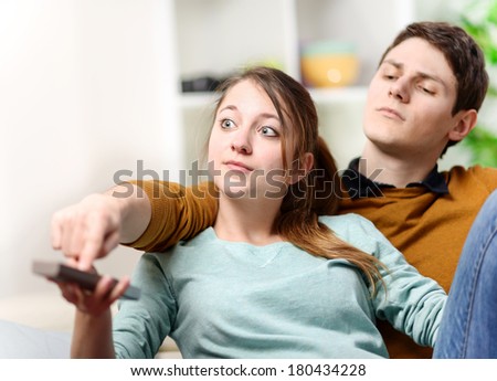 beautiful woman and her husband trying to change tv channel on remote control