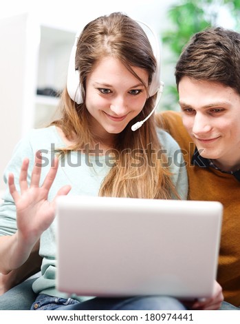 Happy young couple talking through the computer with video chat