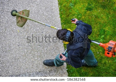 gardener using corded string trimmer in a park