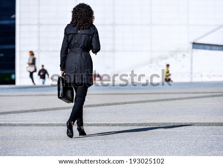 Back view of Young business leader woman walking on the city street