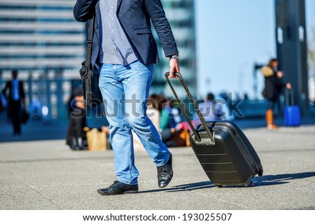 front view of traveler man walking with suitcase in the street