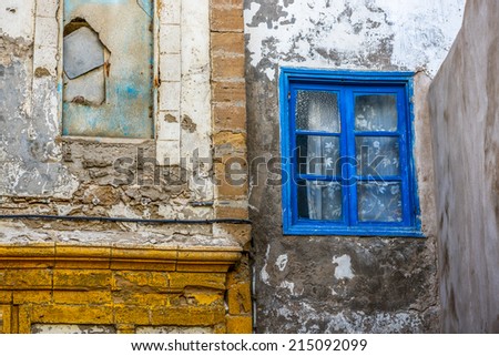 Old building wall with a blue-framed window on the right side