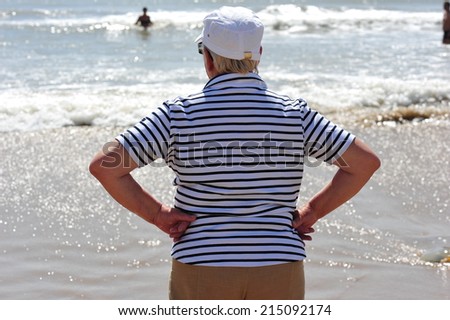 An old man admiring the sea view with his both arms leaned on his sides