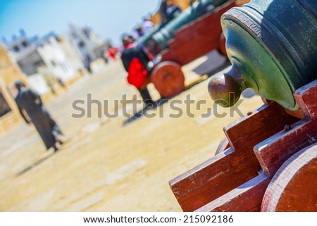 A detail shot of a back end of cannon gun with a blurry view of the street in the background