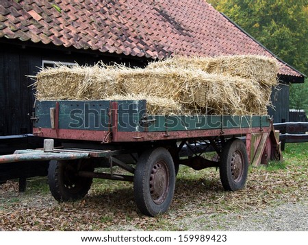Hay wagon with stacked bales at a barn front