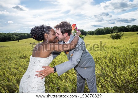 Newly wed interracial bride and groom hugging and kissing