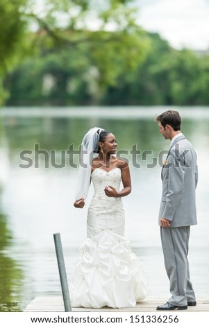 Bride showing off her dress to the groom next to a lake during wedding day