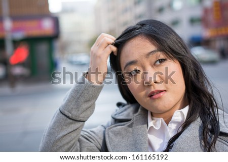 Young Asian woman in coat on a street in a large city