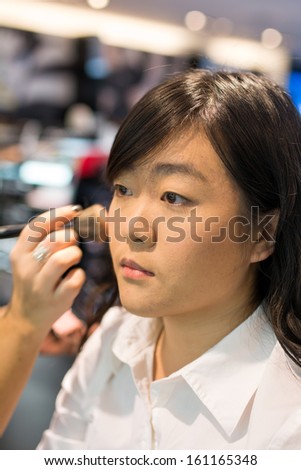 Young Asian woman applying facial powder with a brush