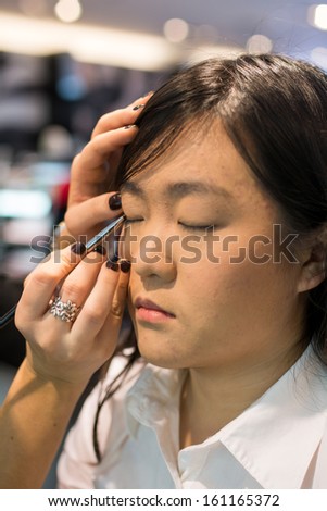 Young Asian woman applying eye liner with a small brush