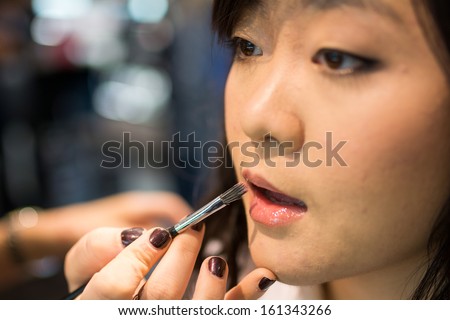 Young Asian woman applying lipstick and other cosmetics