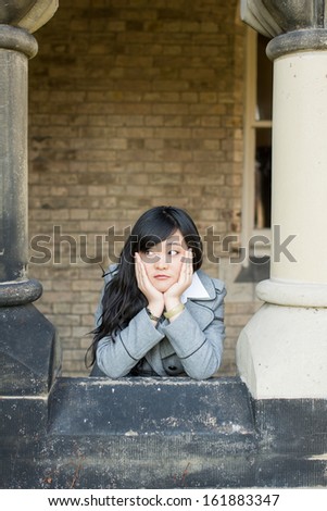 Young woman leaning forward next to stone pillars