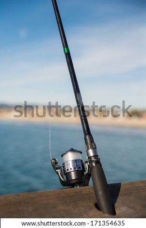 Fishing rod and reel on a wooden bar on a ocean