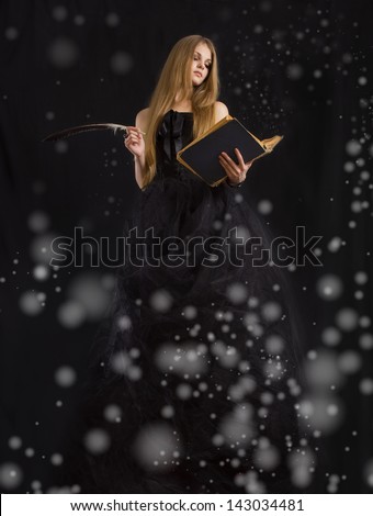 Some magic with book,feather pen and beauty girl.Fine art portrait.Black background