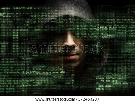 Silhouette of a hacker looking in camera with binary codes from monitor