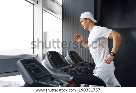 Handsome gym man running on the treadmill