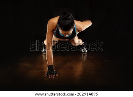 Pushup.Sporty girl doing exercise pushups on wooden floor,studio shot  - stock photo